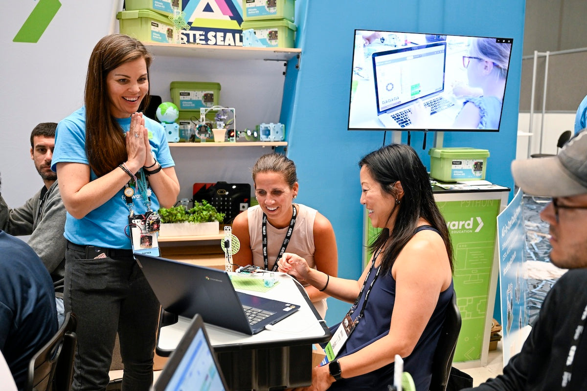 Three female educators at the Forward Education trade show booth in a workshop session