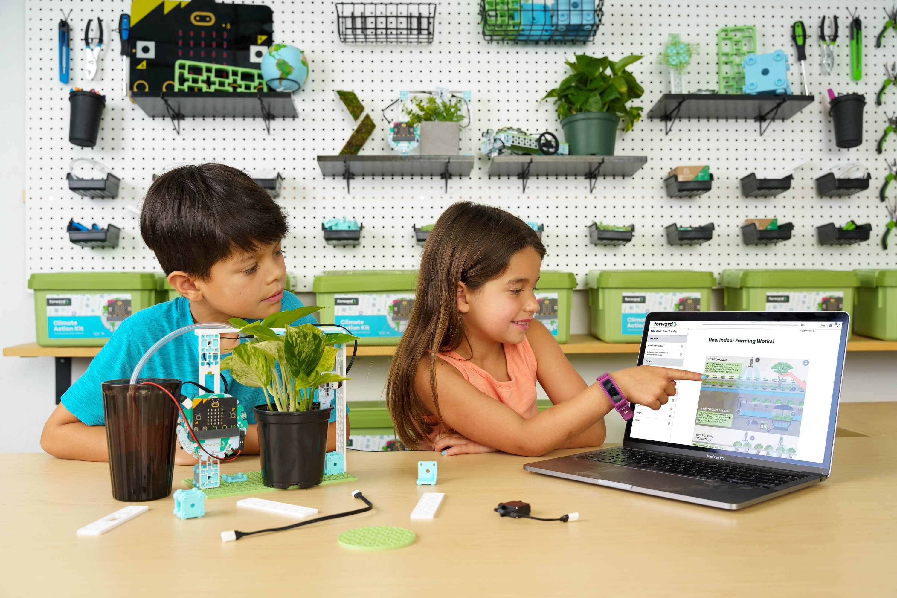 Two students with various Climate Action Kit projects, pointing to the Smart Farming lesson on the laptop